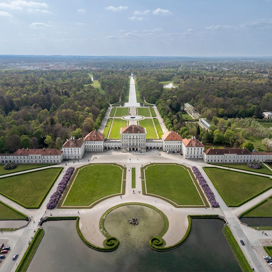 Aerial wide shot of Nymphenburg Palace and its surrounding park grounds on a clear day. 